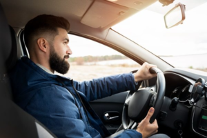 Man driving a car on a road, focused and holding the steering wheel